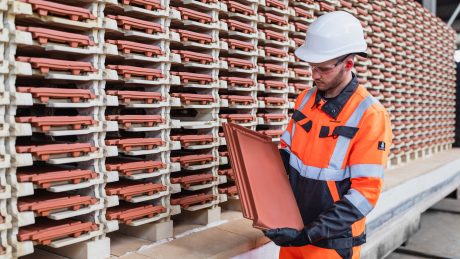 Man inspecting roof tiles at a production facility