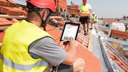 Dachdecker sucht technischen Rat mit Tablet auf einem Dach