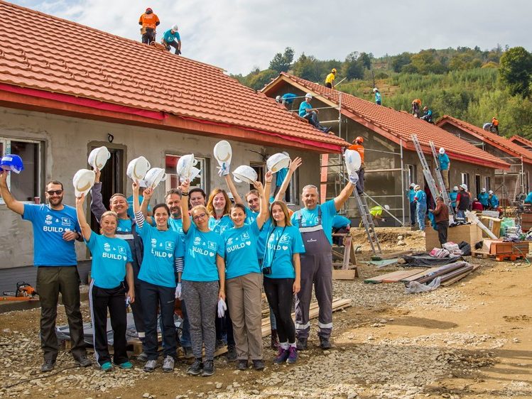 Mehrere Menschen von Habitat for Humanity stehen vor Gebäude