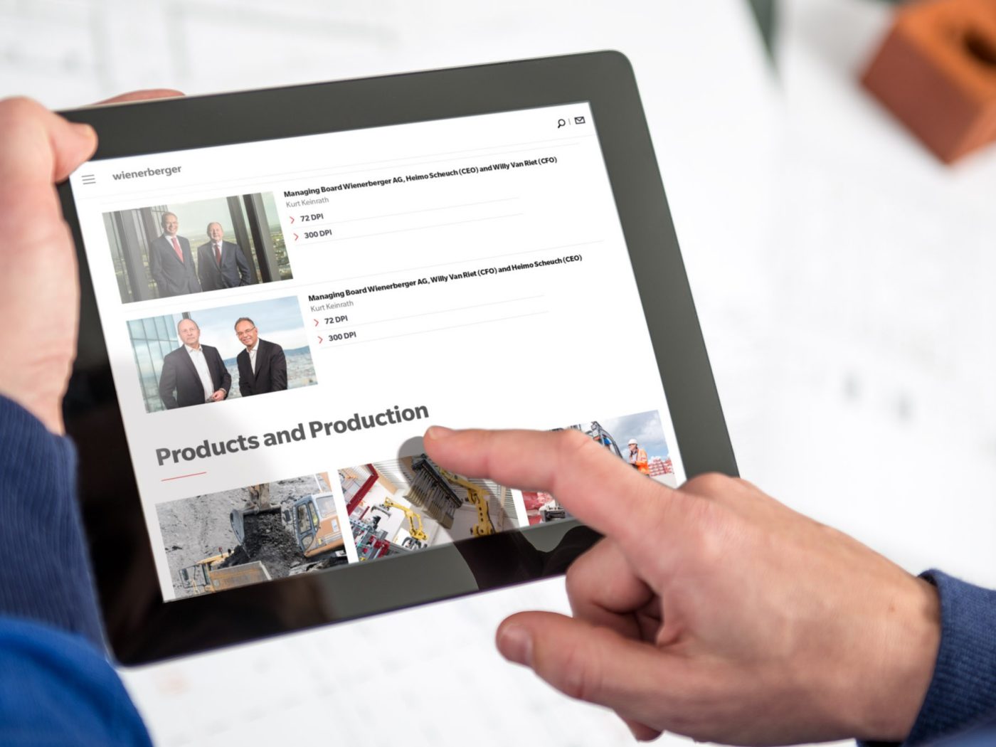 Zwei Hände halten ein Tablet mit der Wienerberger Website