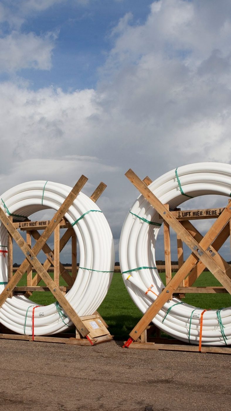 weiße Rohre aufgewickelt; Straße, grüne Wiese, blauer Himmel