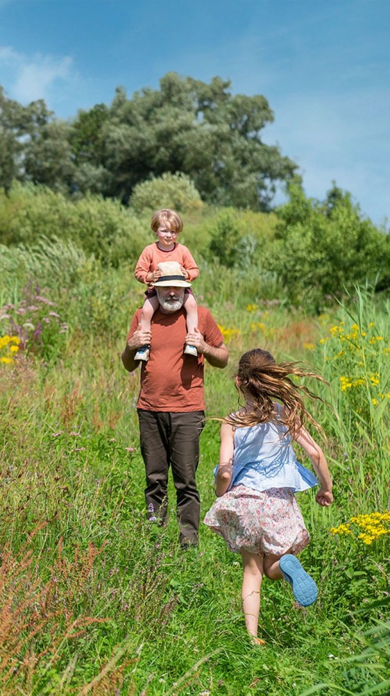 Ein Mann mit zwei Kindern auf einer grünen Wiese