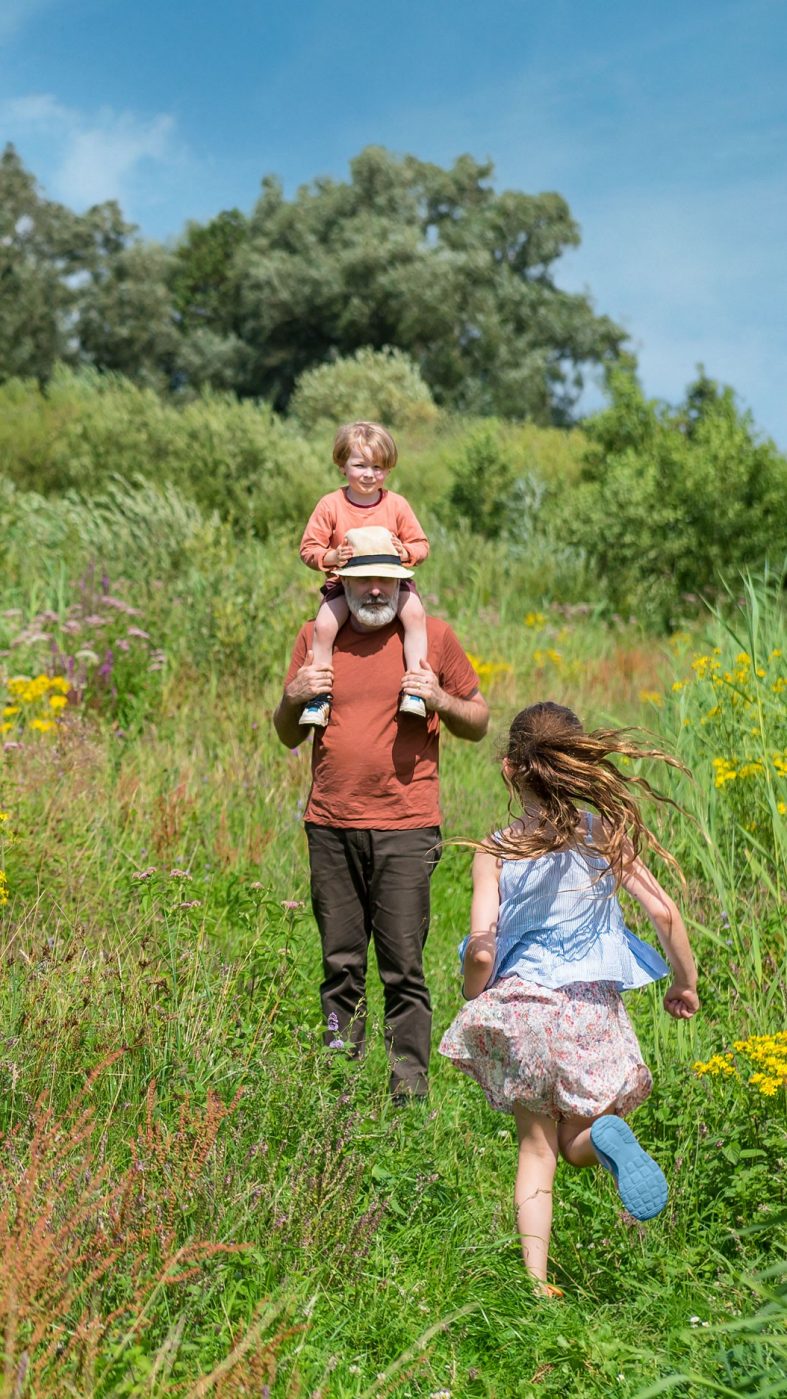 Ein Mann mit zwei Kindern auf einer grünen Wiese