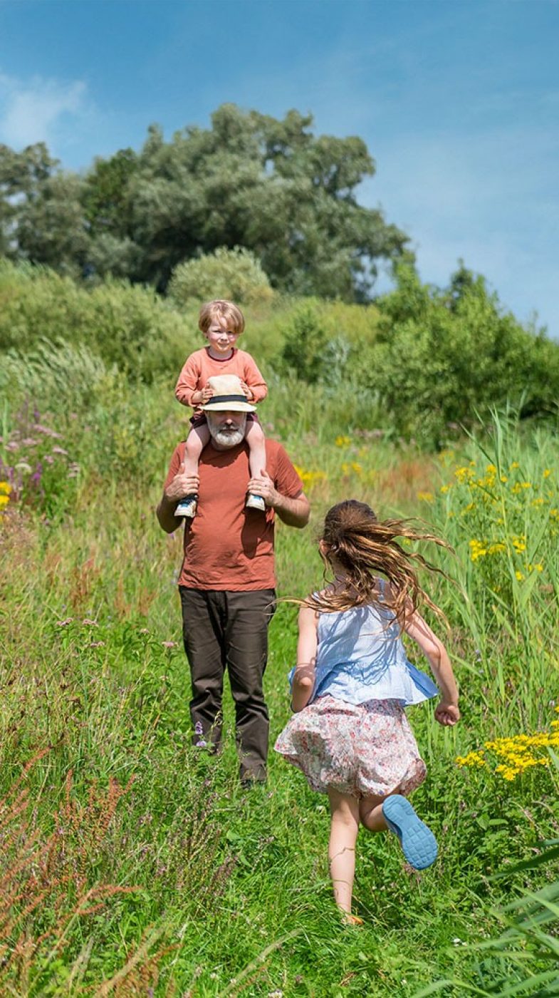 Ein Mann mit zwei Kindern auf einer grünen Wiese