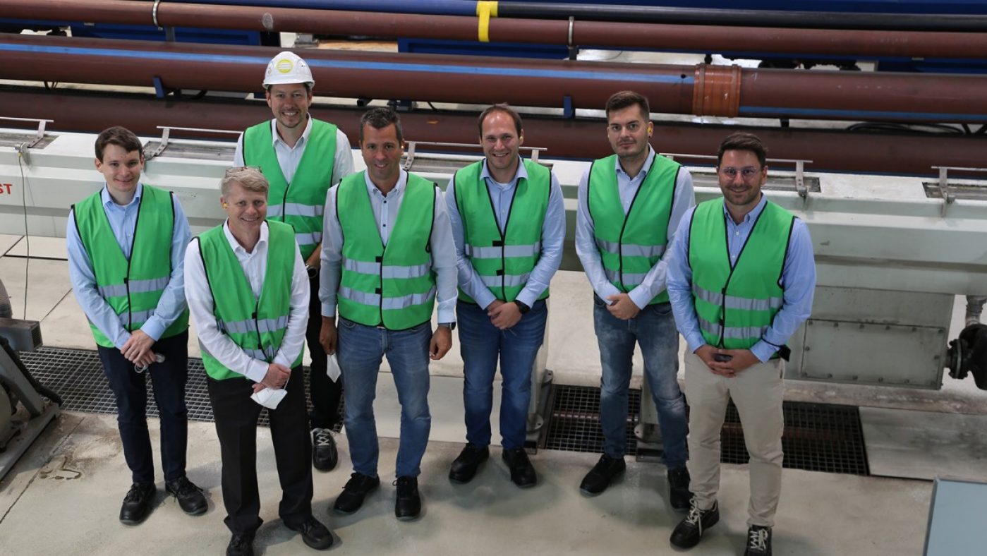 Sieben Männer in grünen Warnwesten in einer Produktionshalle