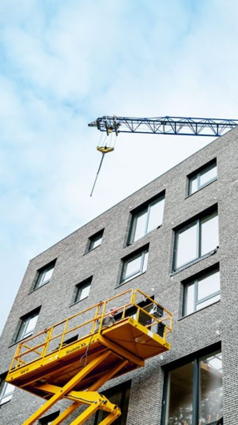 Im Bau befindliches Ziegelgebäude, Baum, blaue Kräne