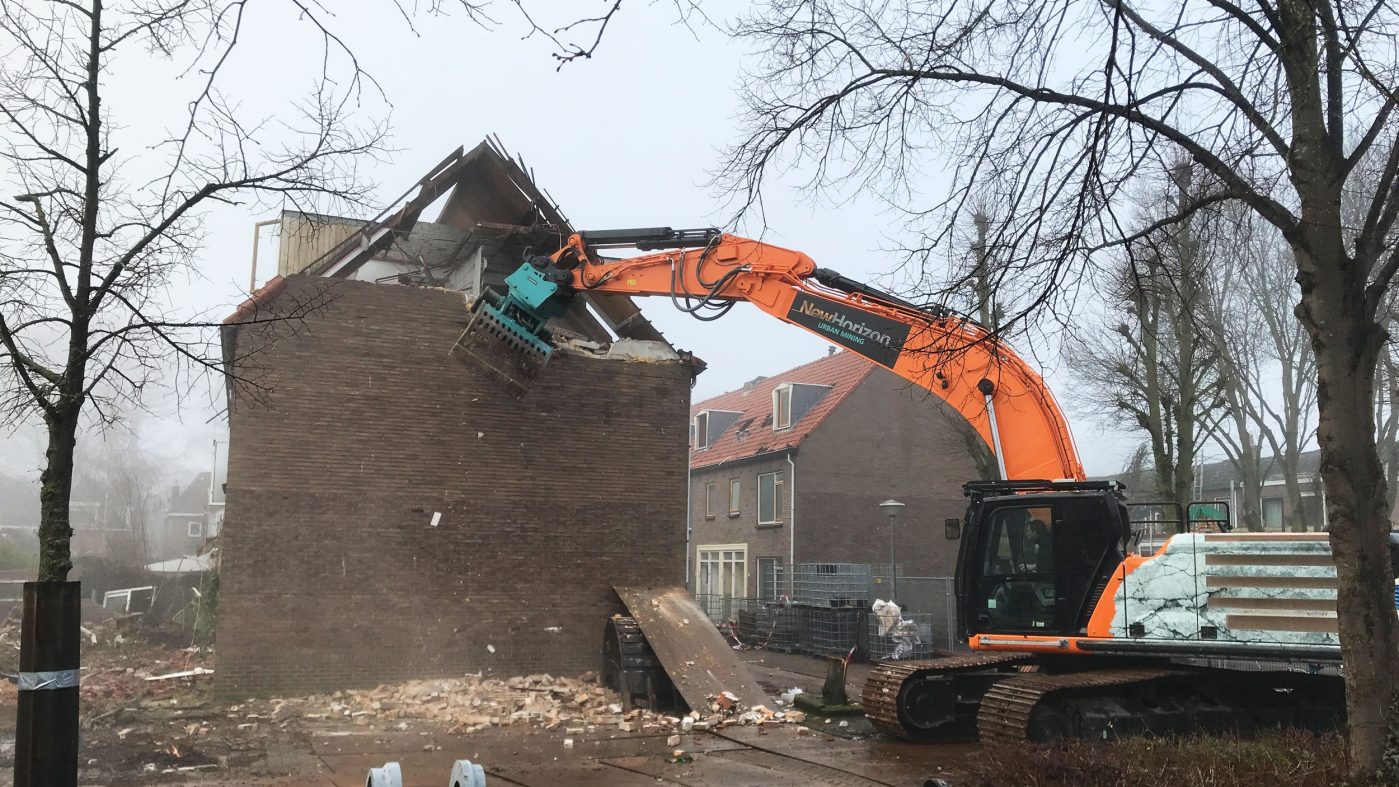 oranger Bagger reißt Gebäude ab