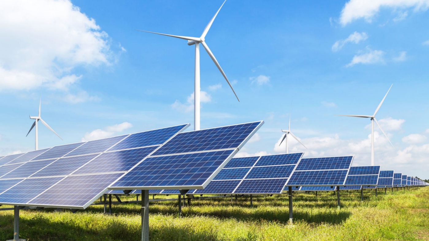 Solarpanels und Windräder auf grüner Wiese