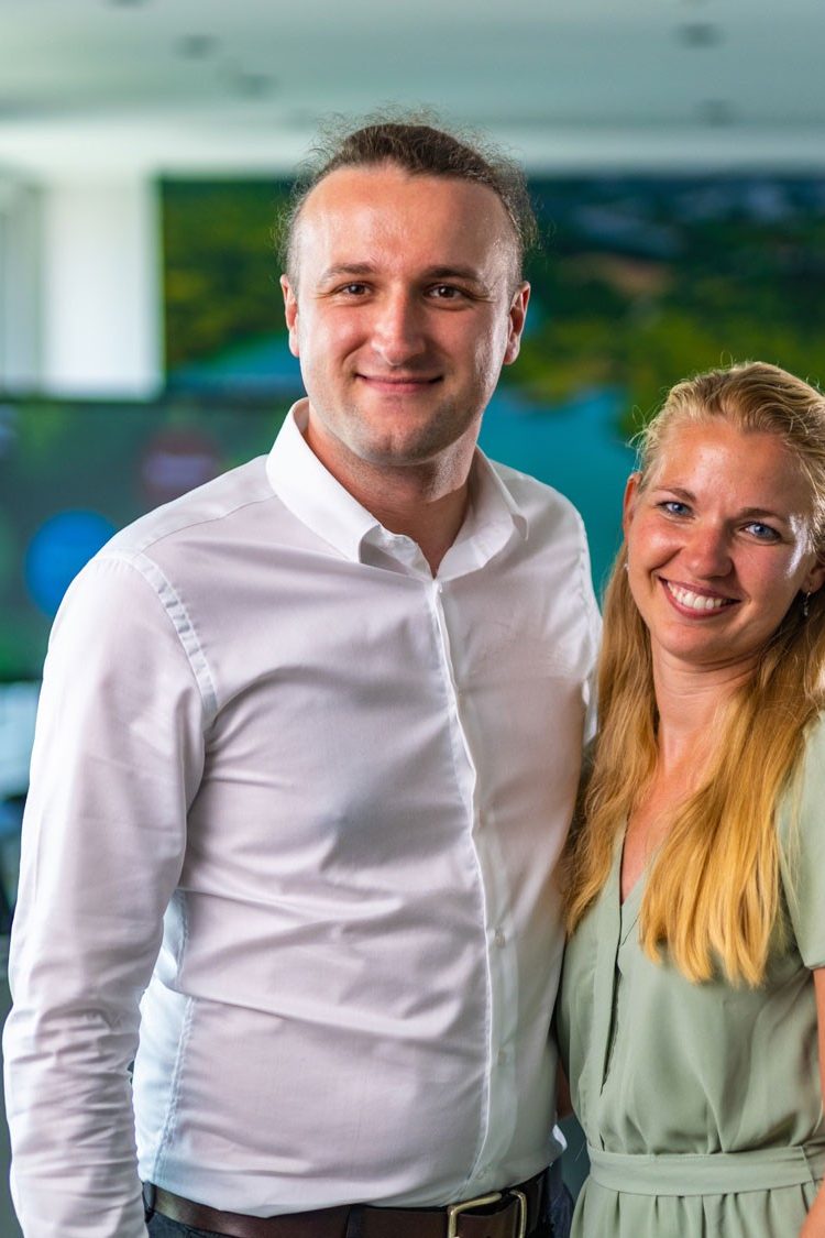 Man and woman laughing into camera in a meeting room