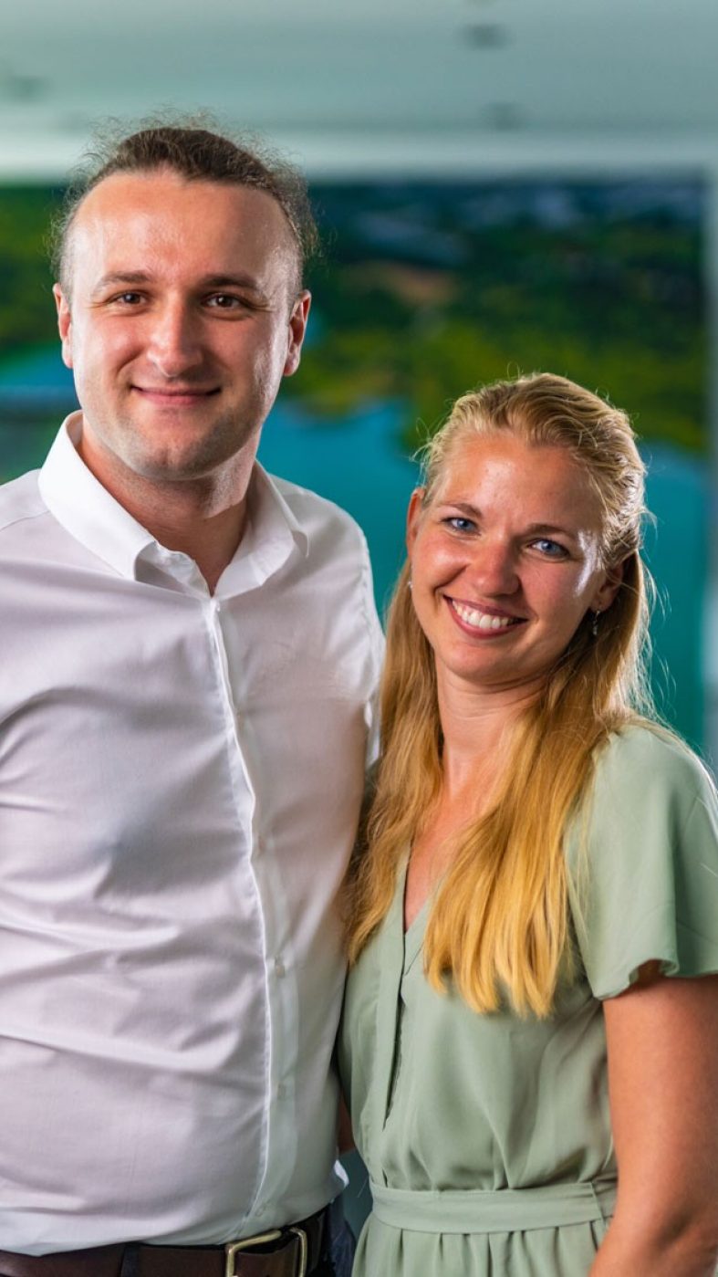Man and woman laughing into camera in a meeting room