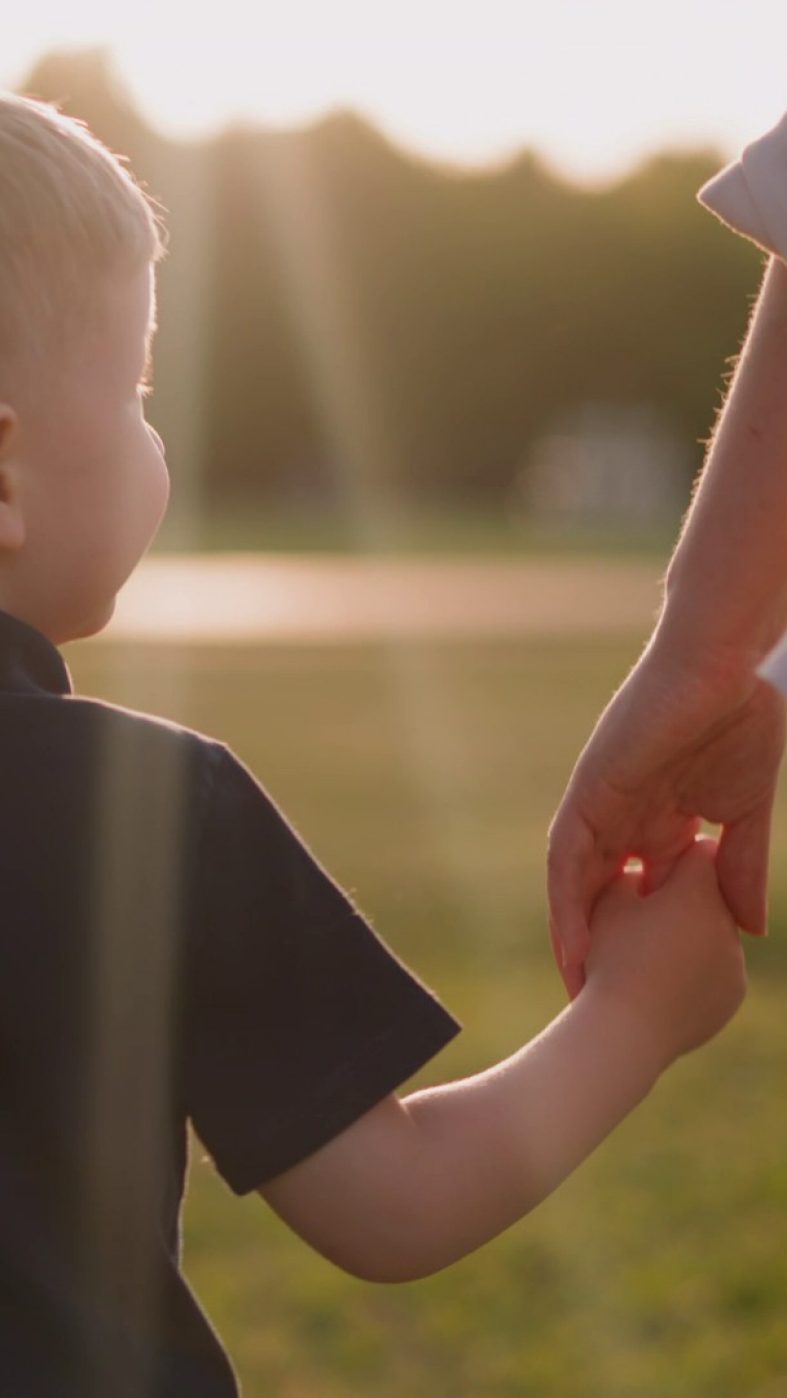 Kind an der Hand im Freien von hinten