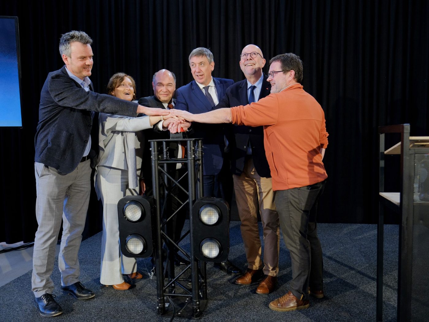 Sechs Personen drücken gemeinsam auf einen roten Button