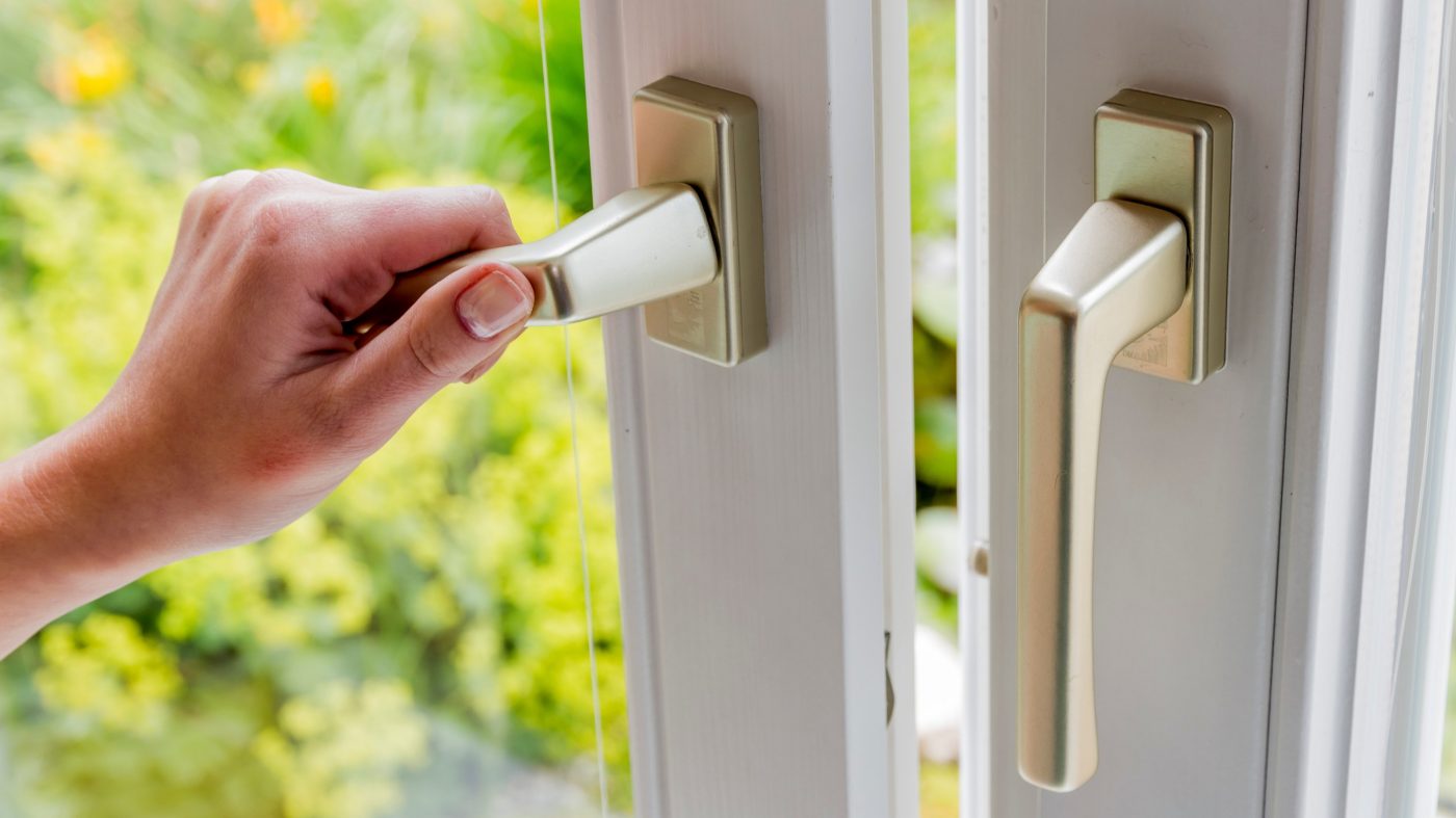 Frau öffnet Fenster und lässt Luft herein