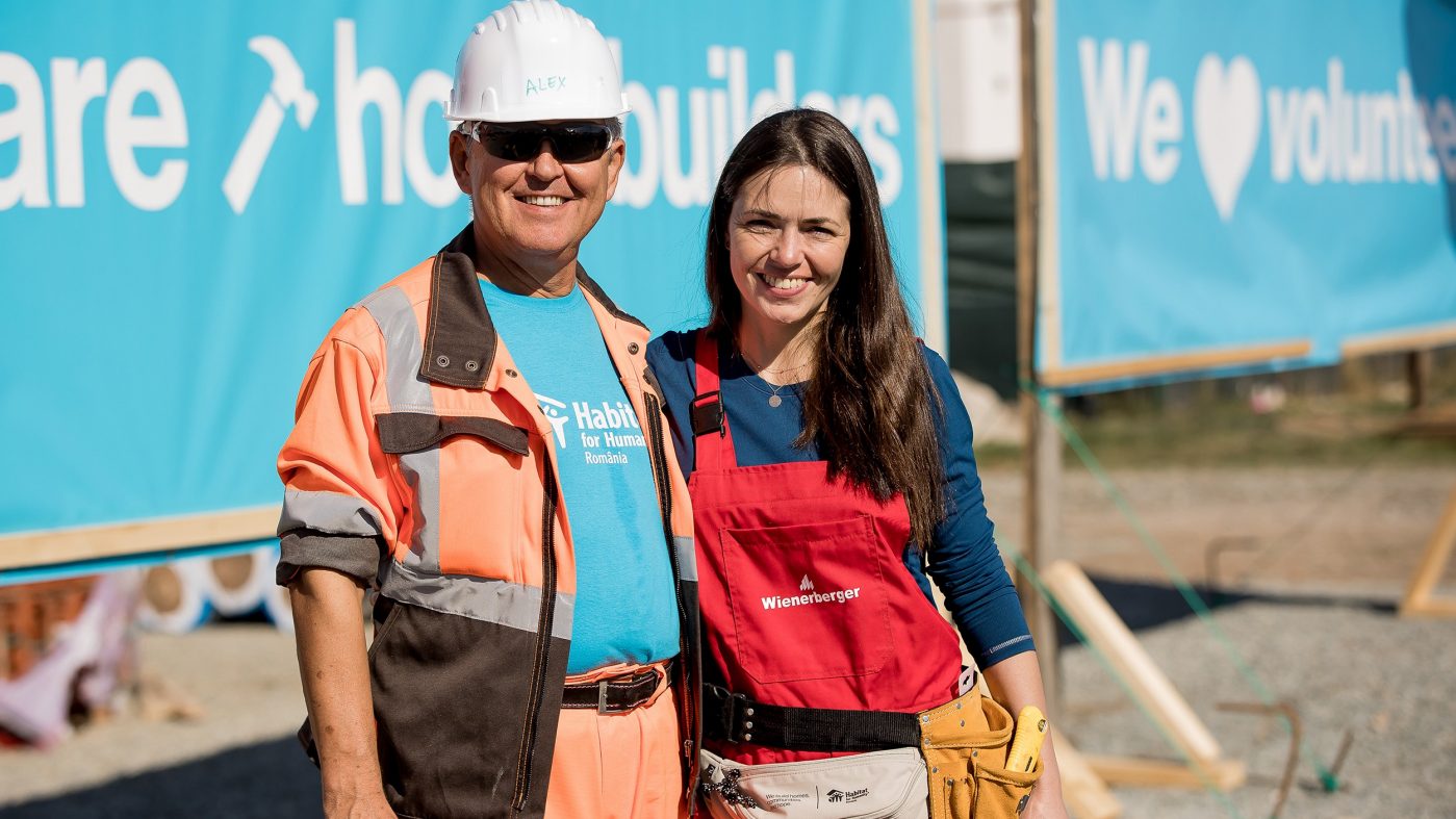 Zwei Personen lachen in die Kamera, Baustelle, Helm, Latzhose