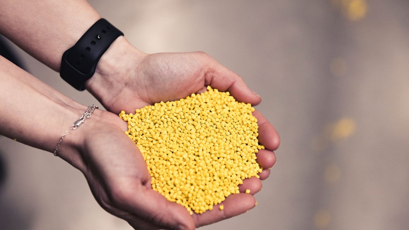 Hände halten gelben Plastikgranulat
