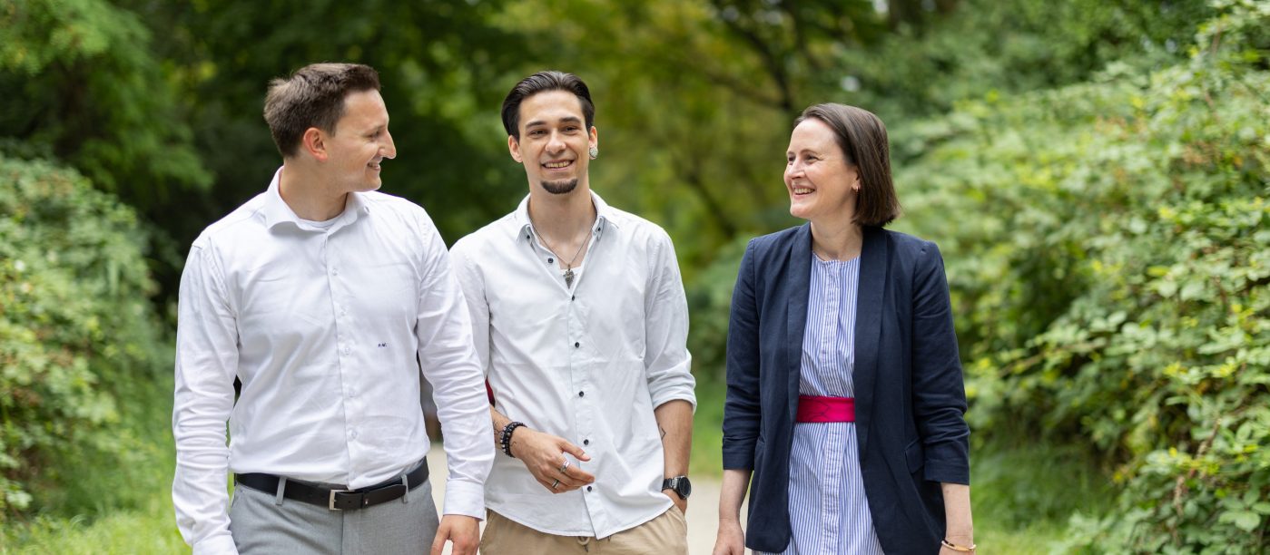 Drei Menschen gehen in einem Park