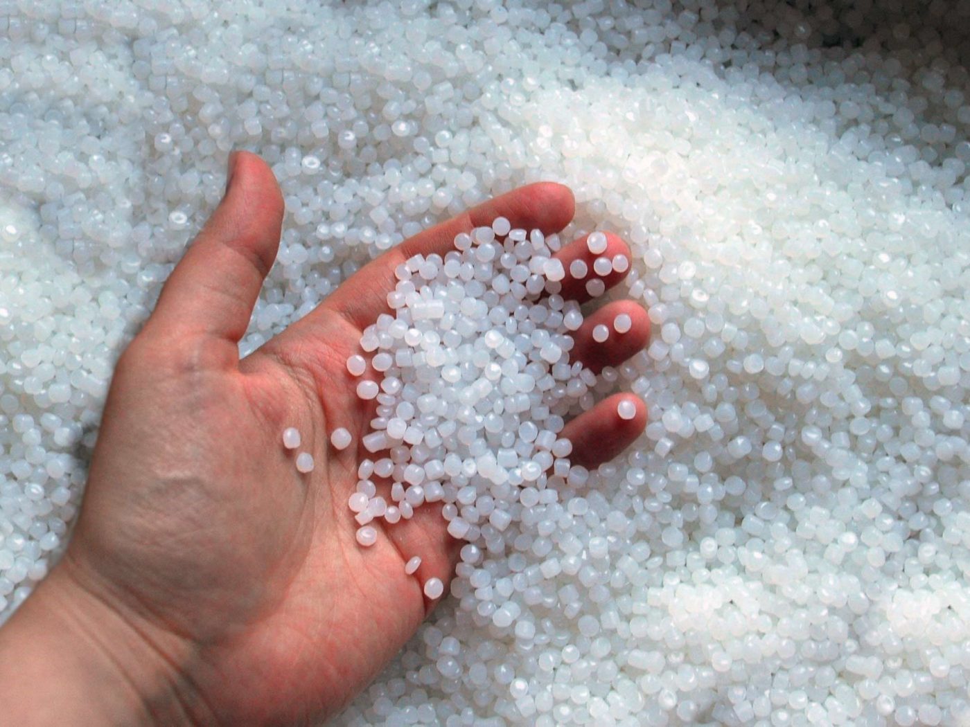 Hand in Plastikgranulat