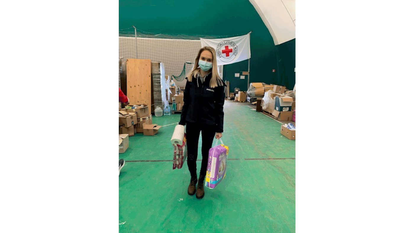 A woman with a mask carries relief supplies