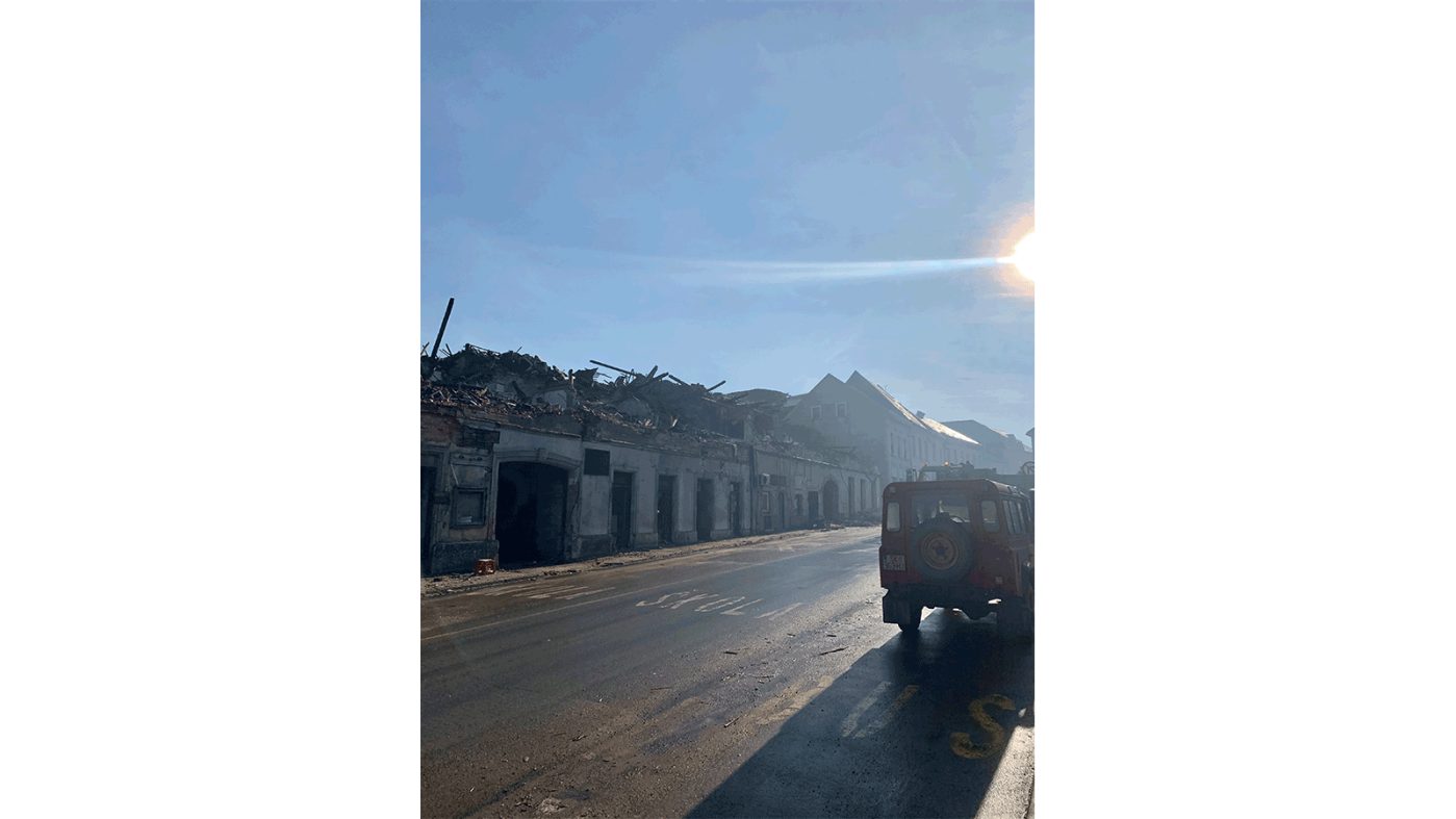 Street with destroid houses and a parked car