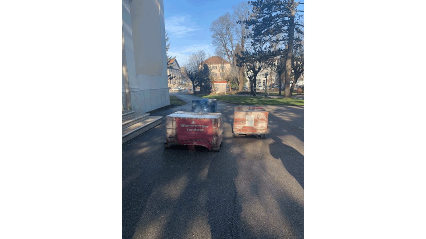 Three pallets with Tondach clay roof tiles in front of a church