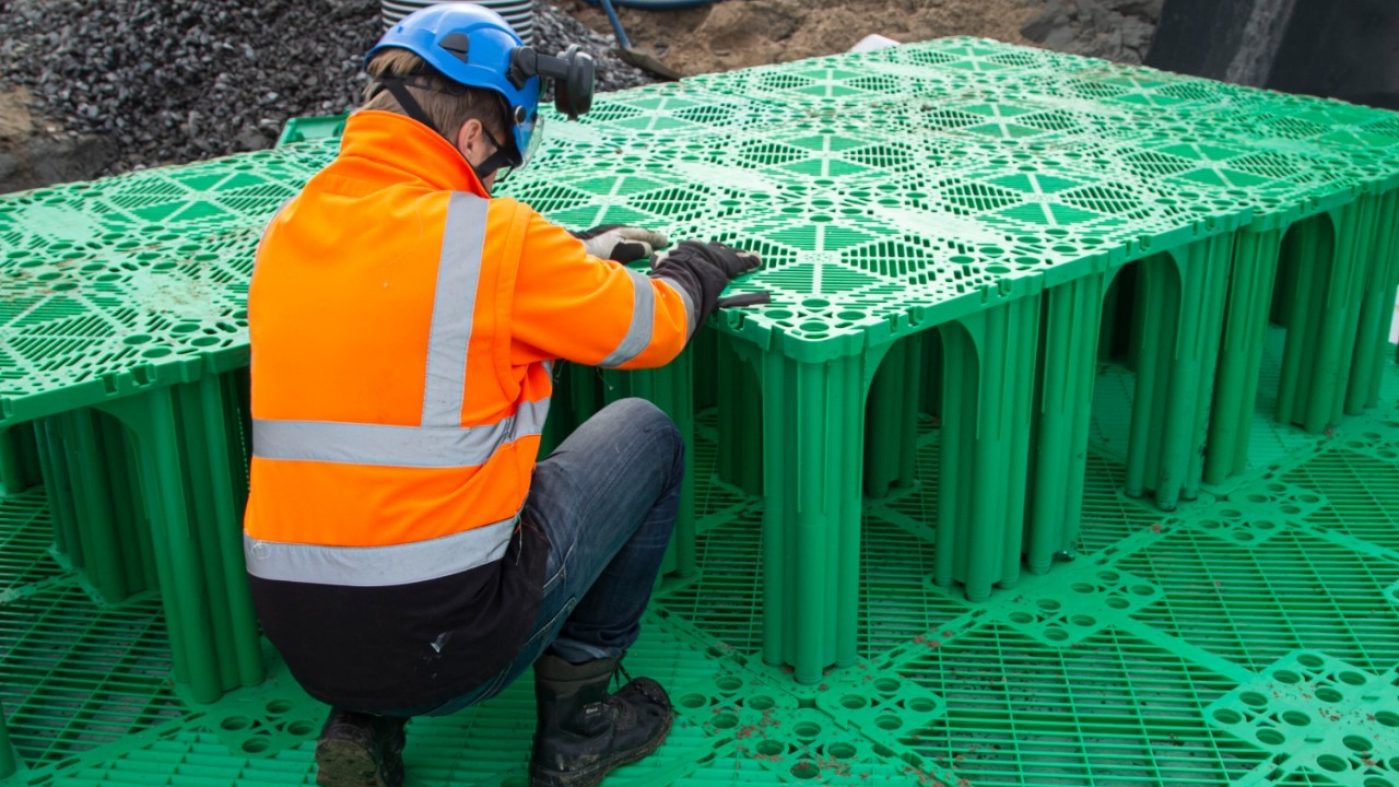 man with orange jacket installing green stormboxes