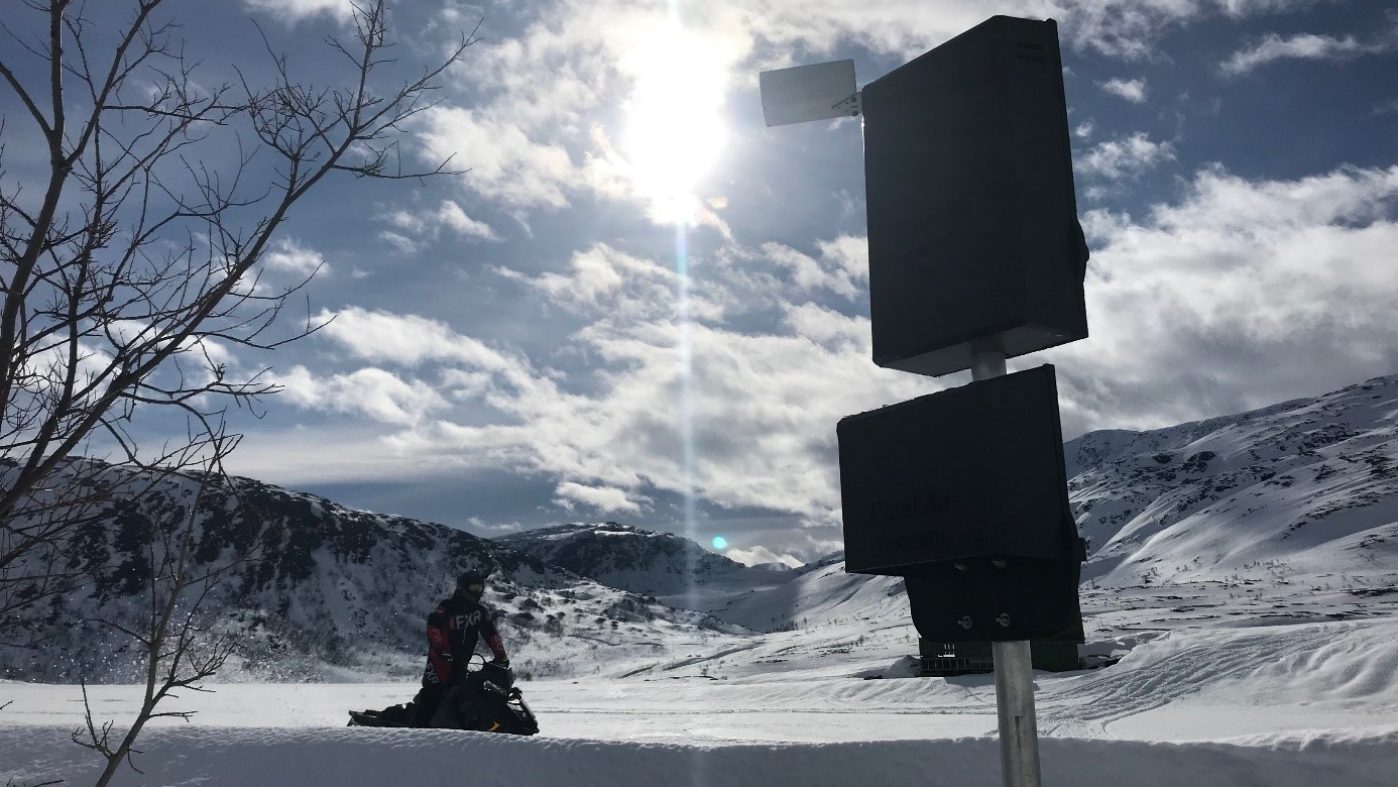 Man rides snowmobile to a measuring station