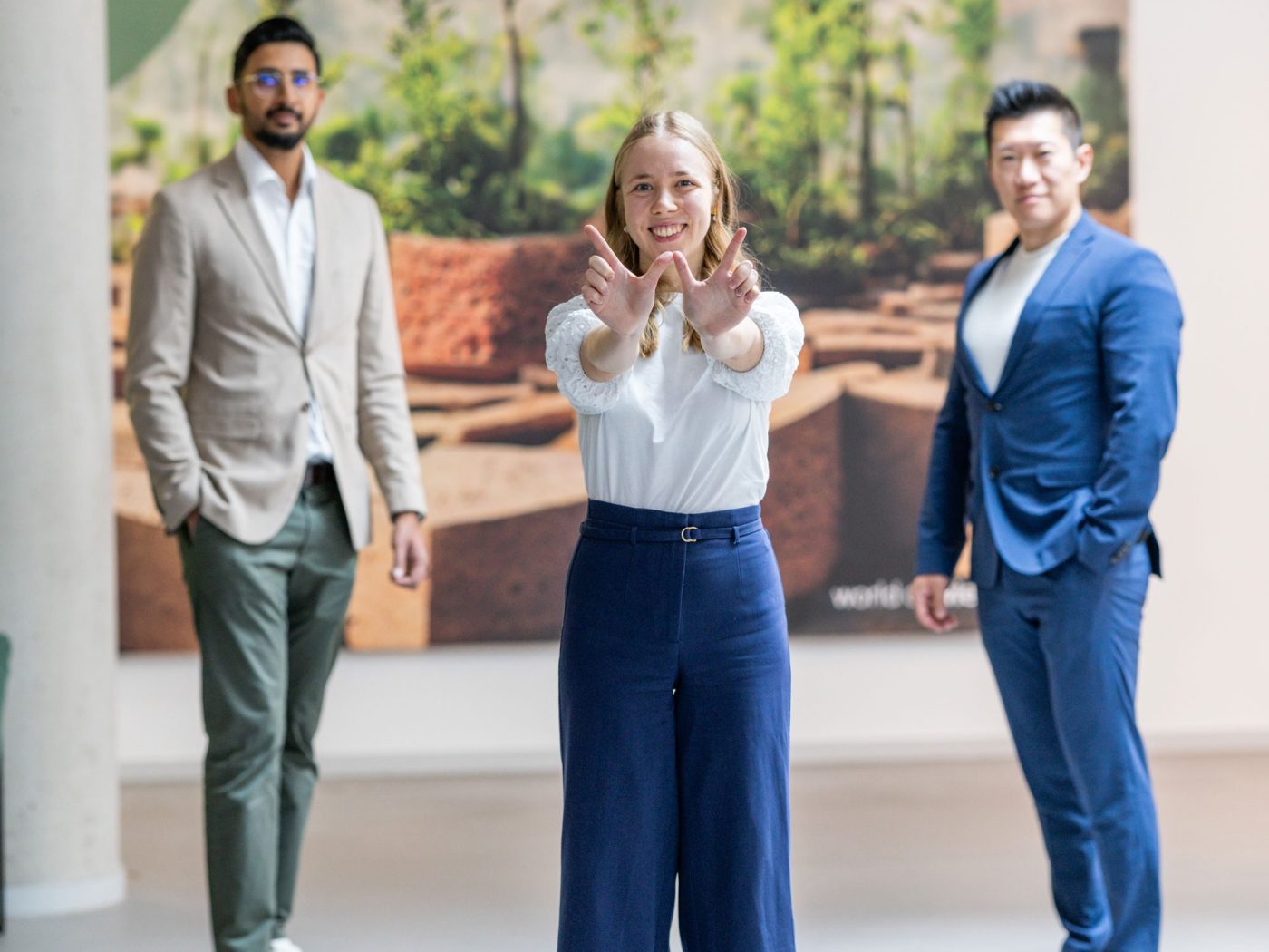 three people standing in the wienerberger lobby looking at the camera, one showing  a "W" with her fingers