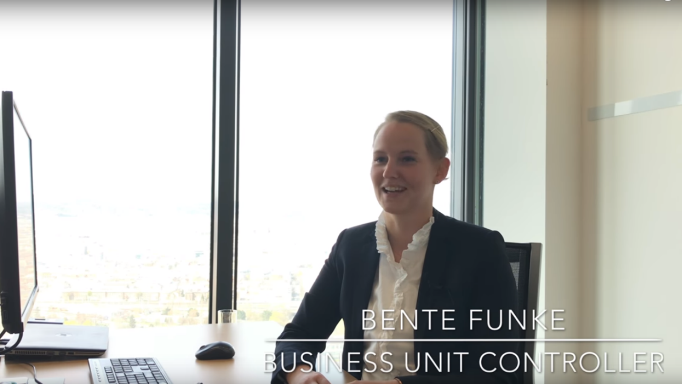 woman in black blazer in an office, desk, talking
