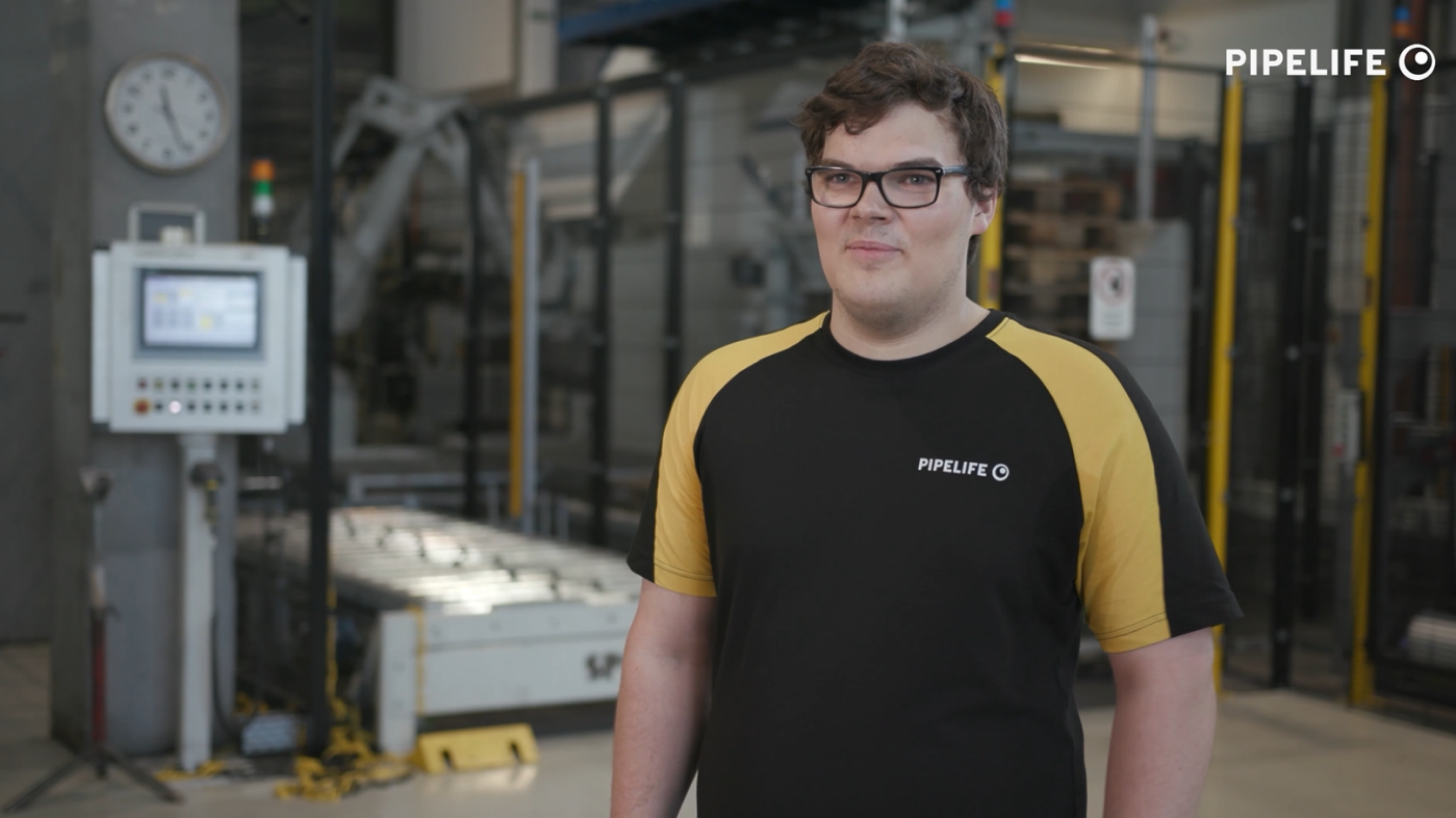 Man with glasses in front of a machine in production hall