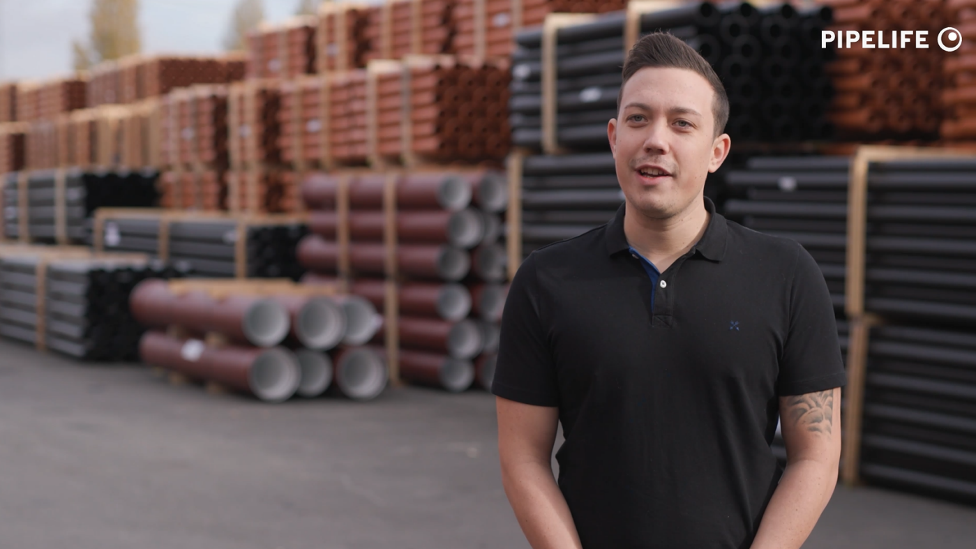 Man in black T-shirt at a storage place for plastic pipes