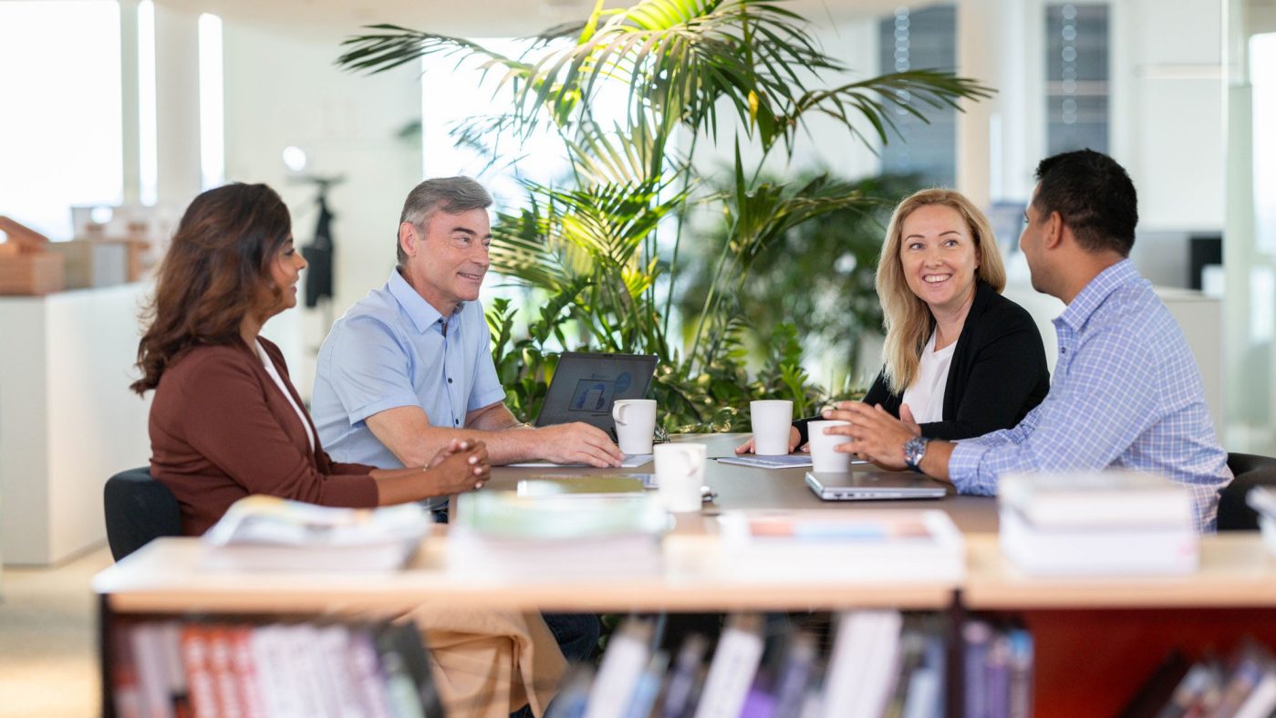 Four people sitting on a table talking