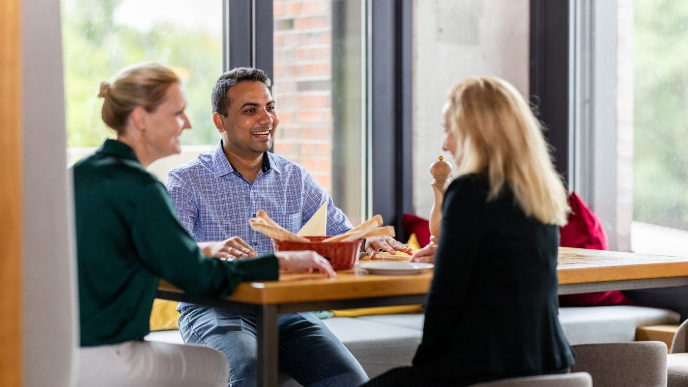 Three people sitting on a table, laughing