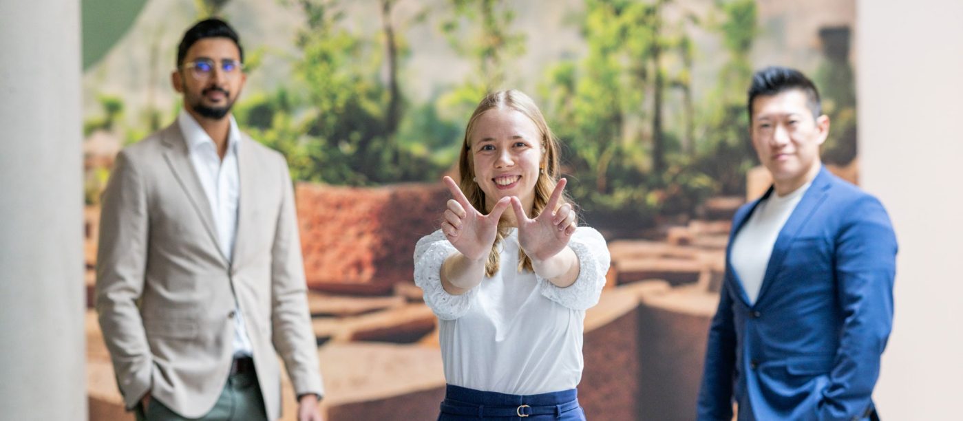 three people standing in the wienerberger lobby looking at the camera, one showing a "W" with her fingers