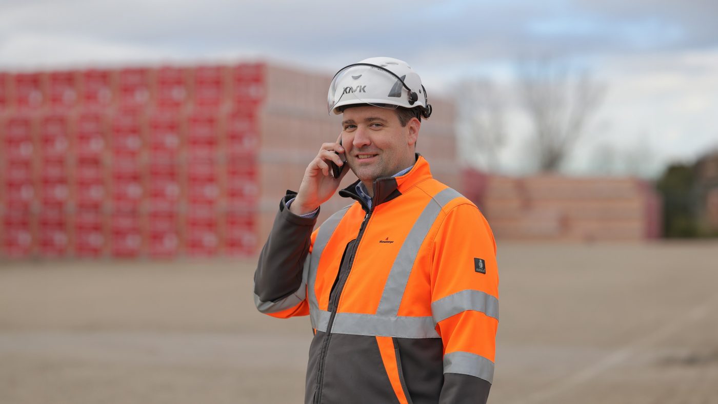 Man in protective clothing, on the phone, storage yard