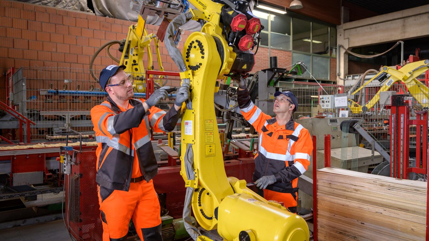 Manufacturing two men working on a robot in a factory