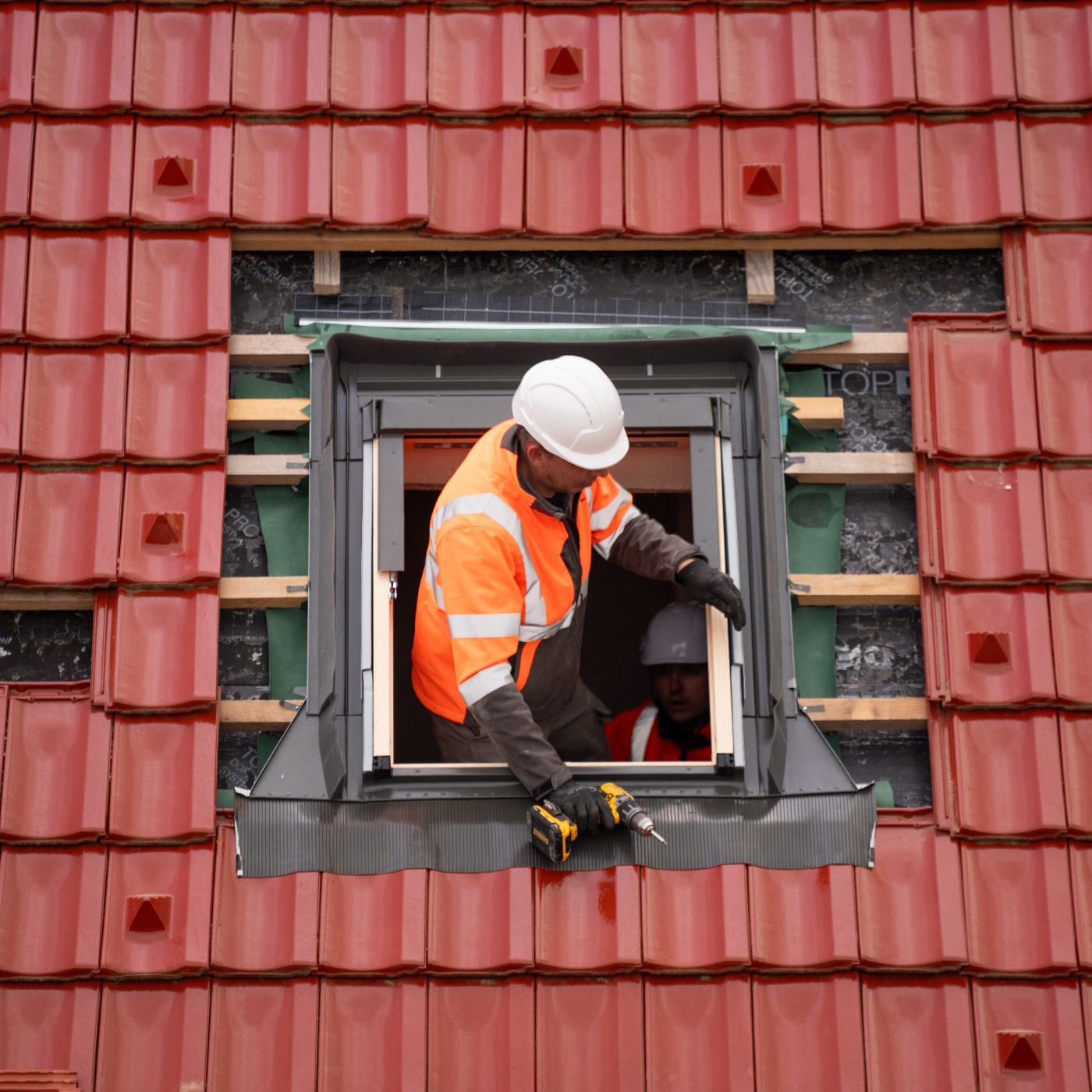 Man installing roof tiles around window