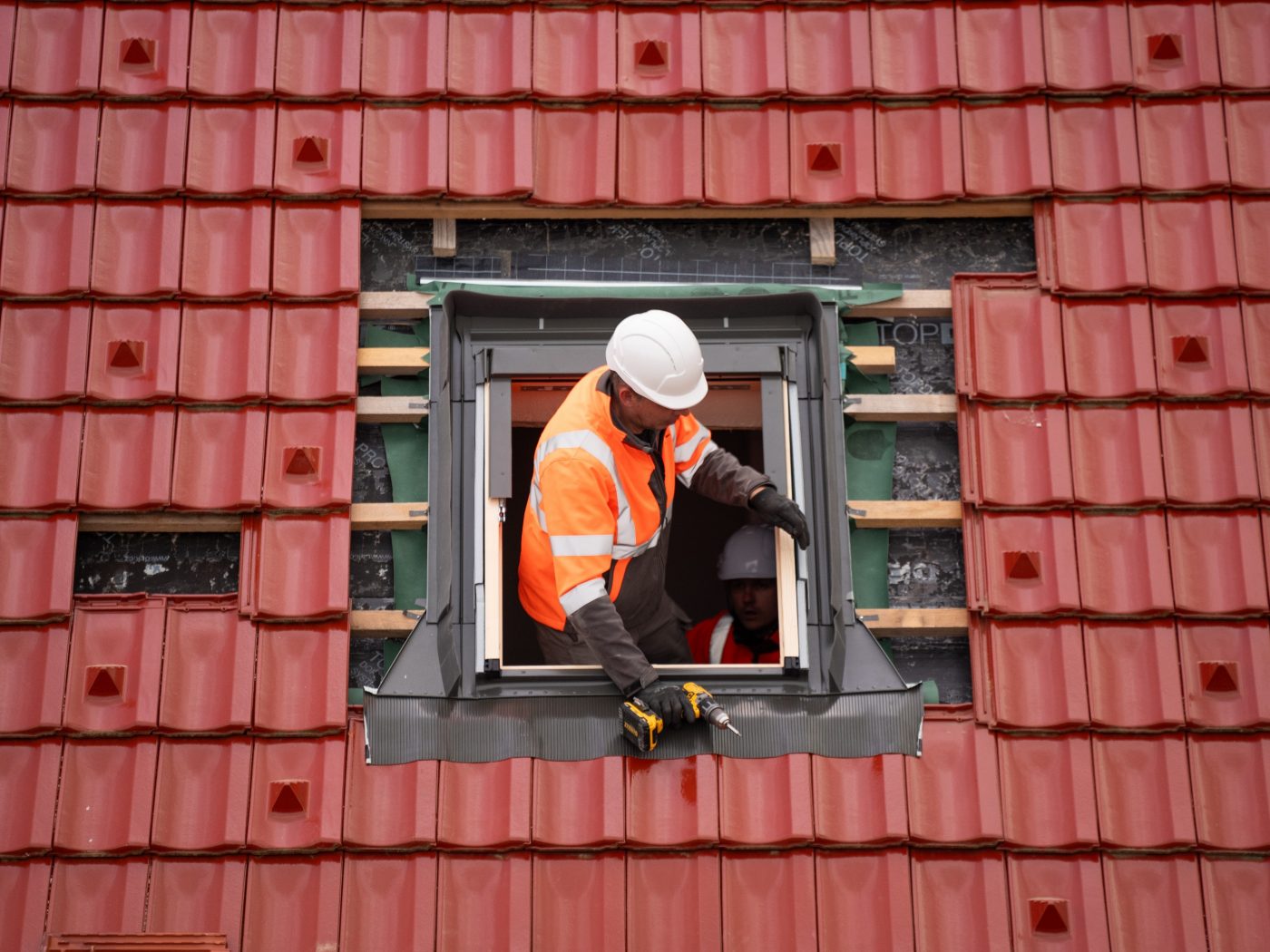 Man installing roof tiles around window