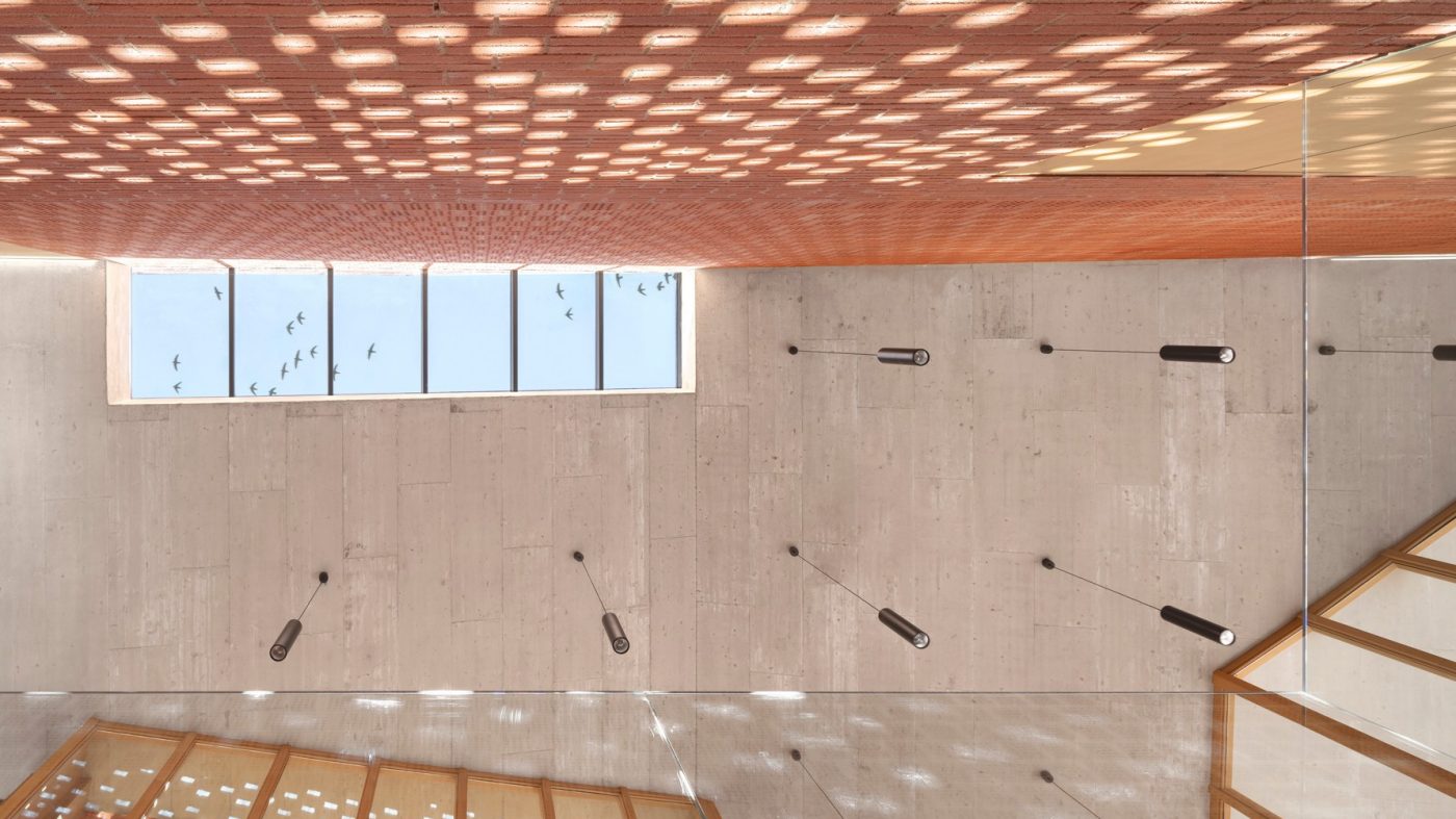 Under view of a concrete ceiling in a hall, brick walls, light play, ceiling windows, lamps