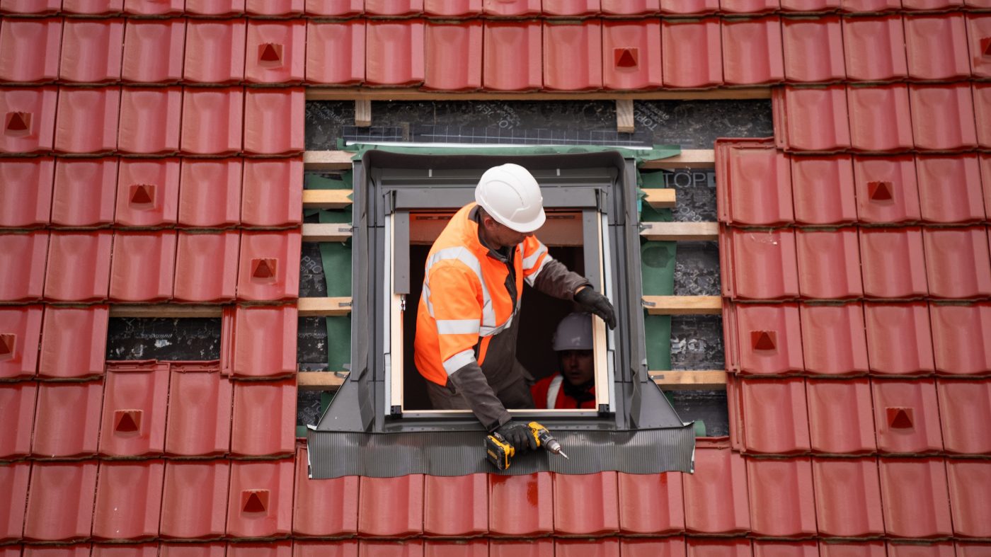Man installing roof tiles around window