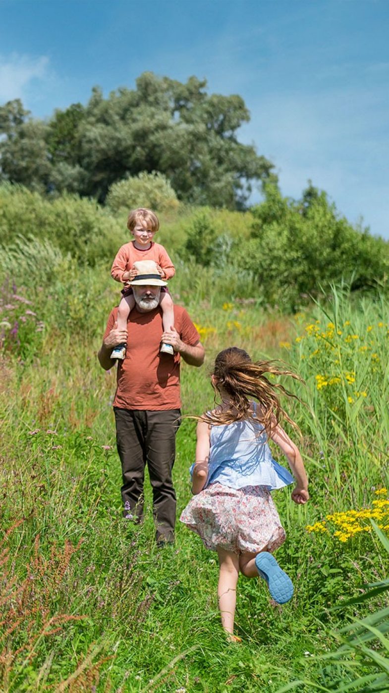 A man and two children on a green meadow