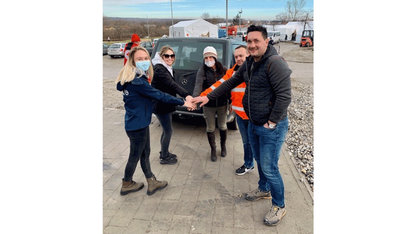 Five people standing in a circle and putting their hands together