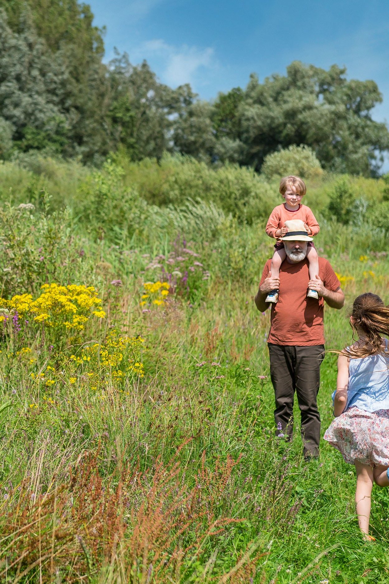A man and two children on a green meadow