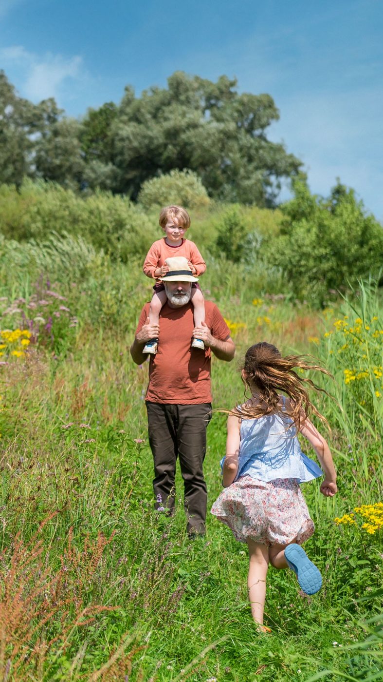 A man and two children on a green meadow