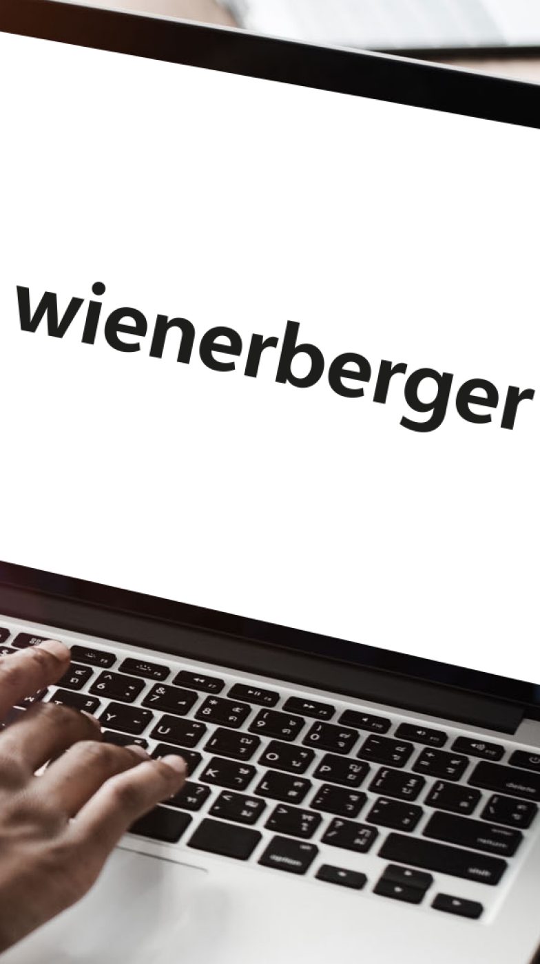 Hand on a laptop displaying the Wienerberger logo