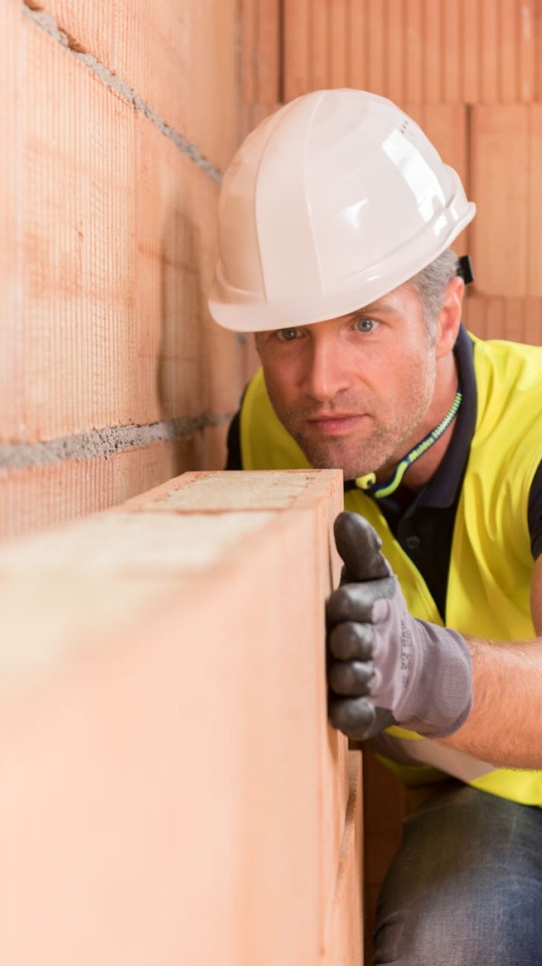 man with white helmet in front of a brick wall