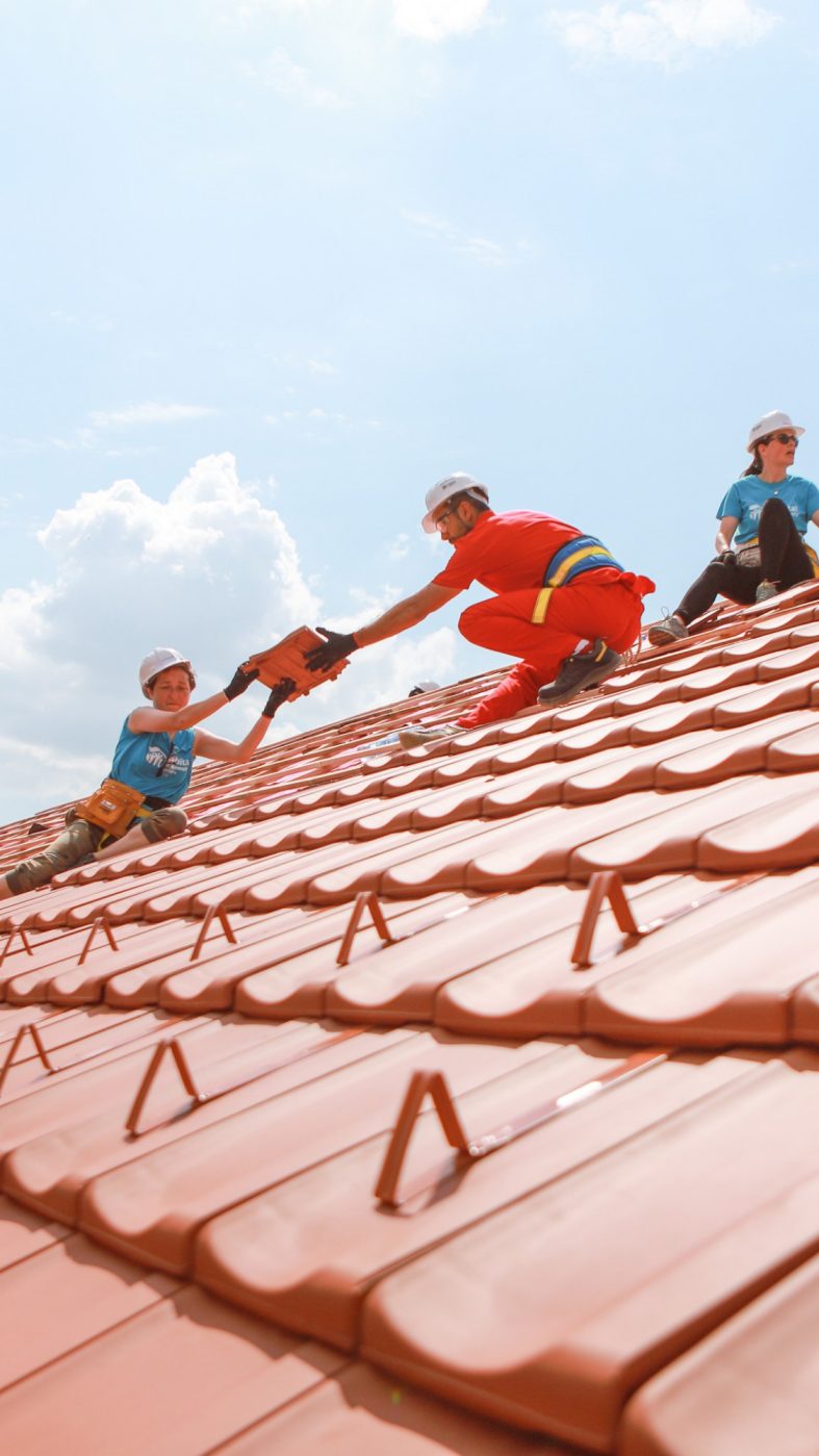 people cover a roof together