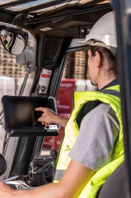 Man sits in forklift and taps on screen