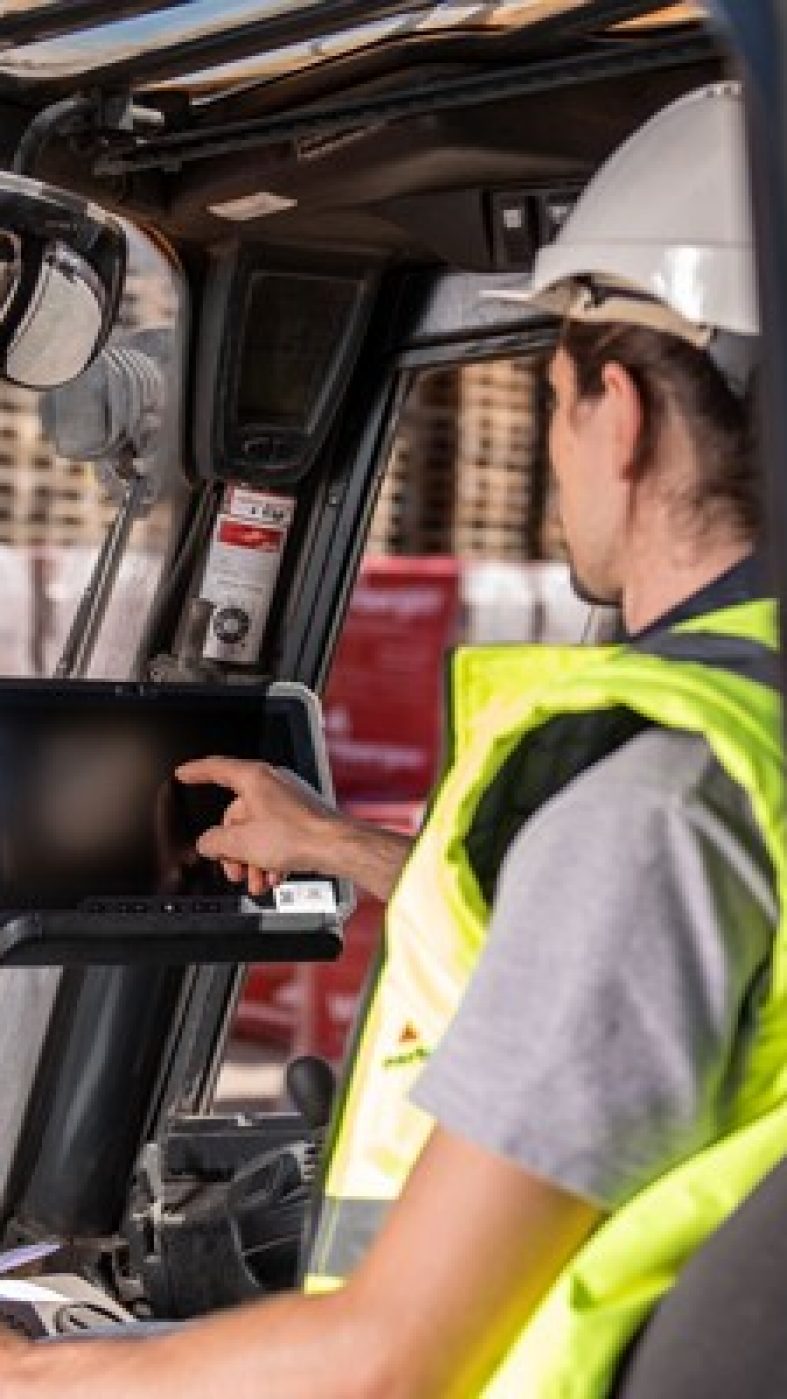 Man sits in forklift and taps on screen