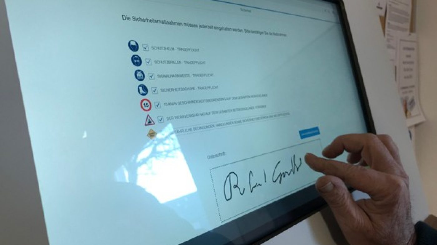 Someone signs a document on a screen