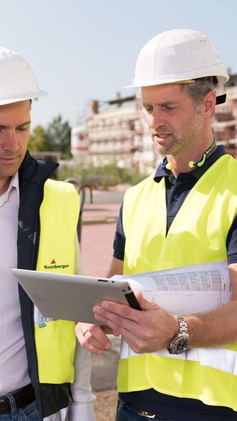 Two men with safety vest, helmet and a tablet